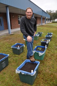 Rex Stanford with "grow boxes" made from former recycling containers.